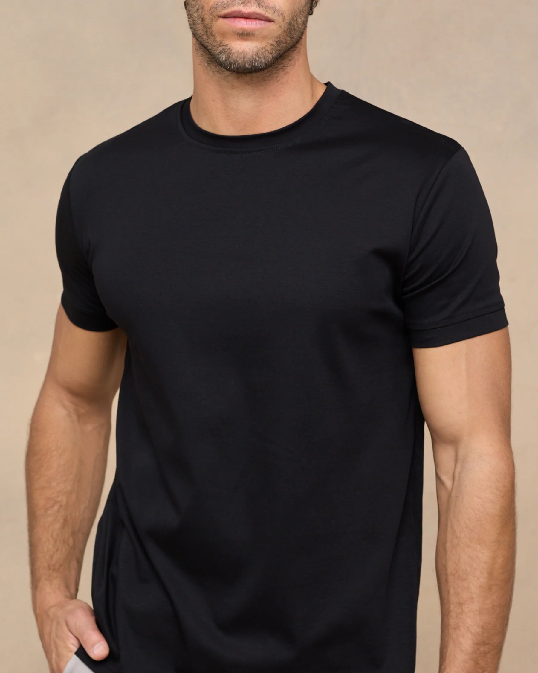 Man wearing a black t-shirt against a beige background