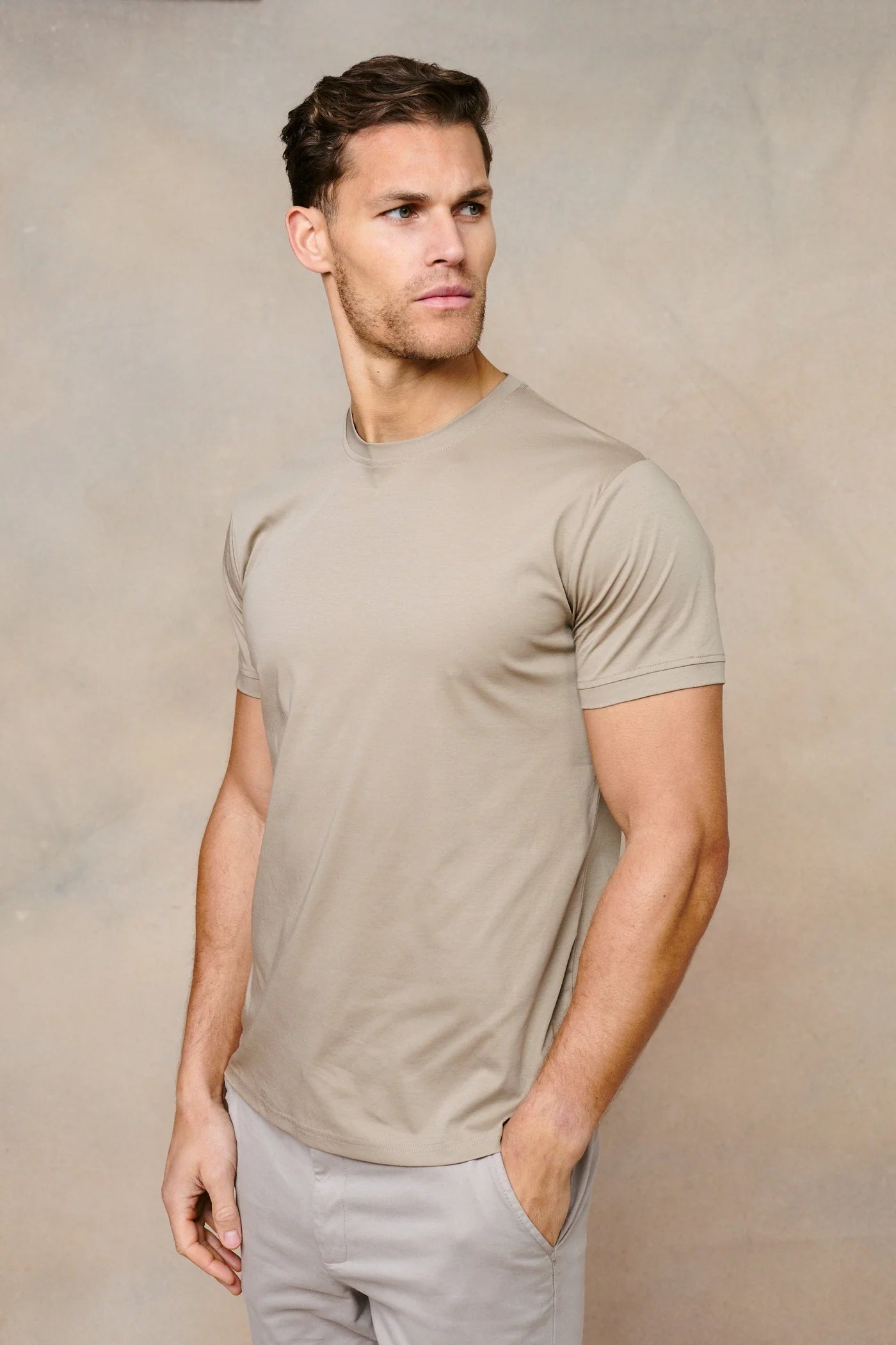 Man wearing a beige t-shirt against a neutral background