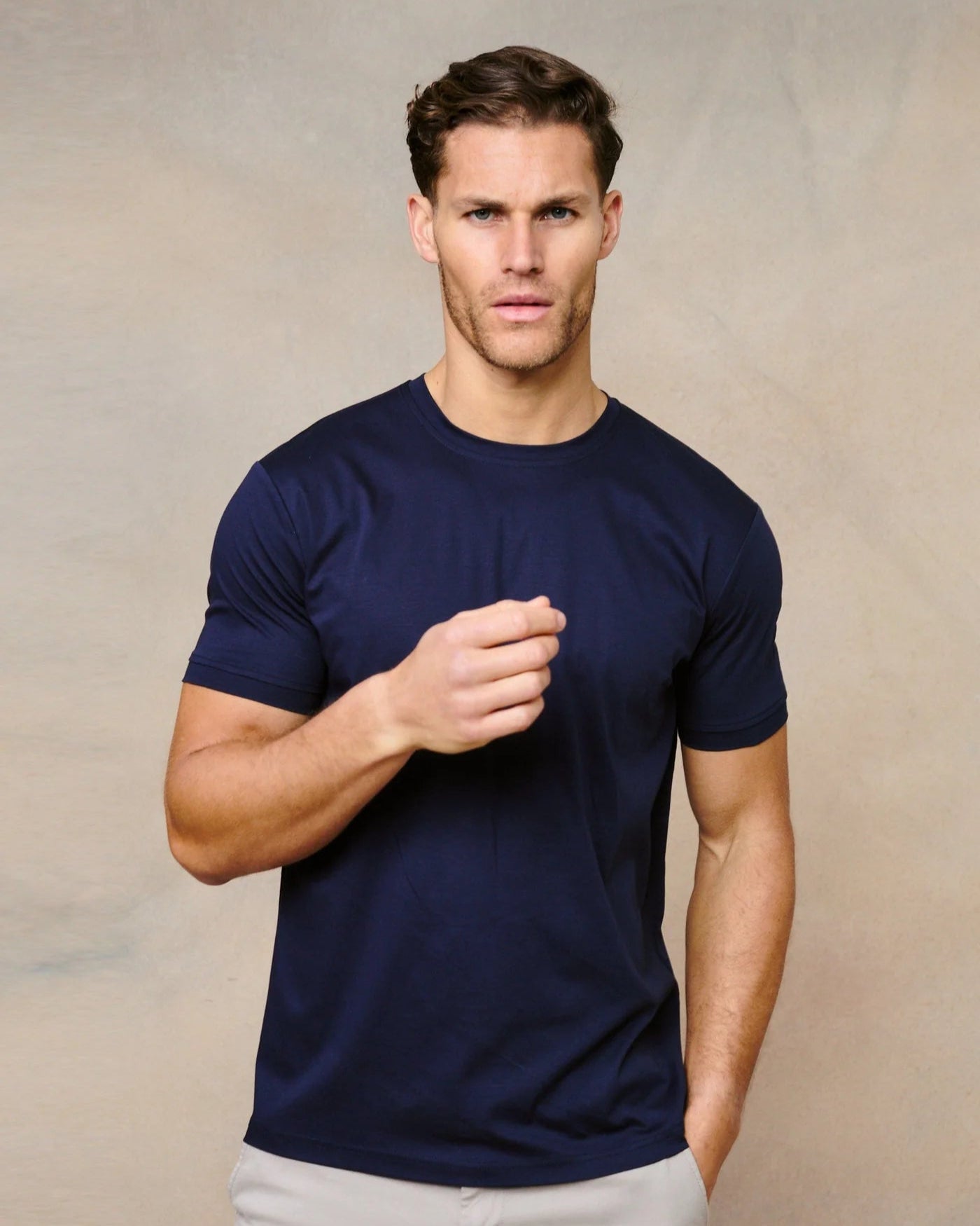 Man wearing a navy blue t-shirt against a beige background