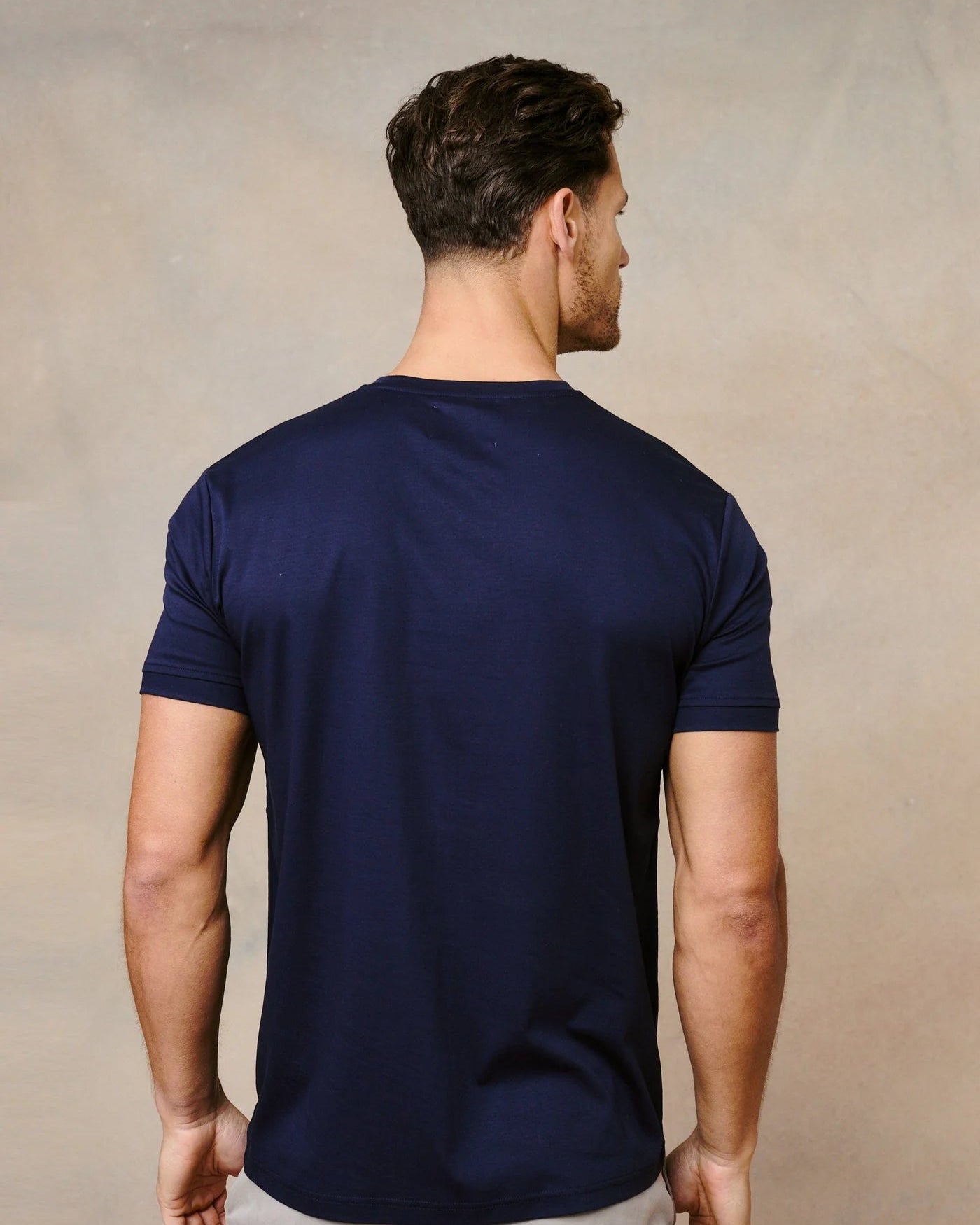 Man wearing a navy blue t-shirt against a beige background