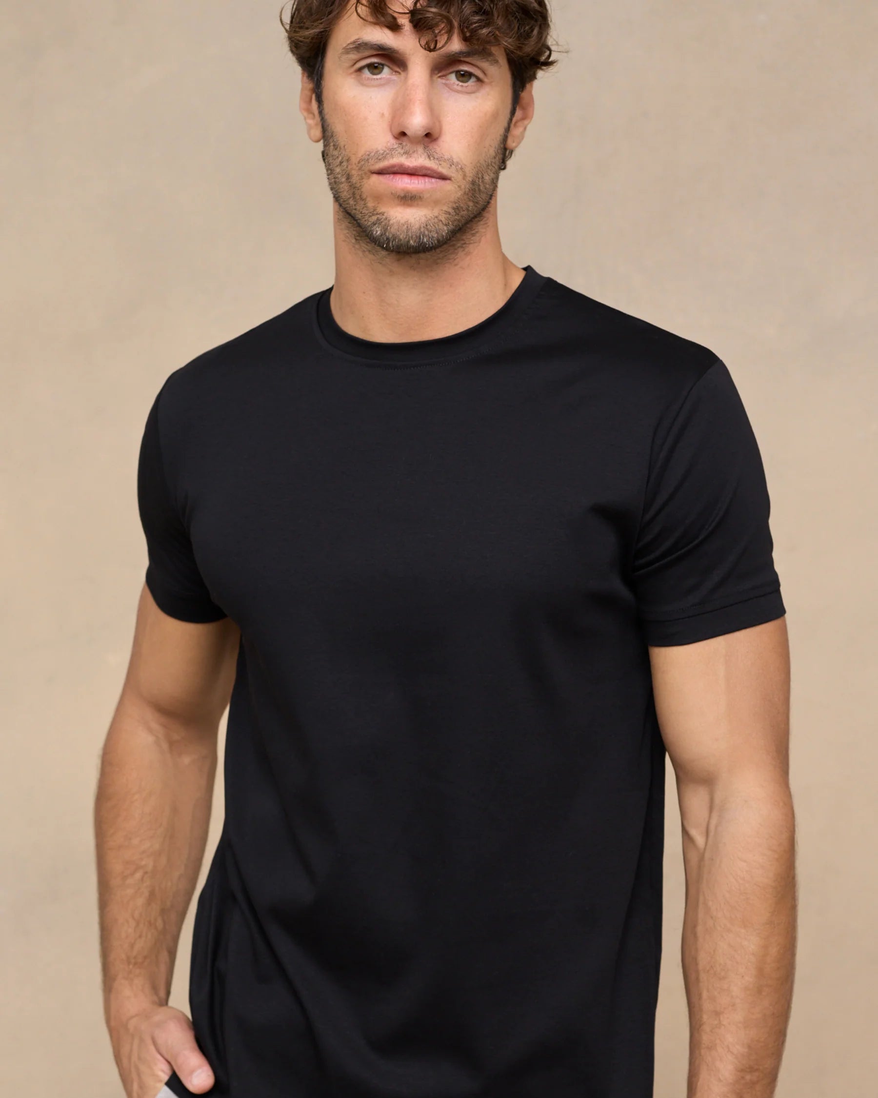 Man wearing a black t-shirt against a beige background