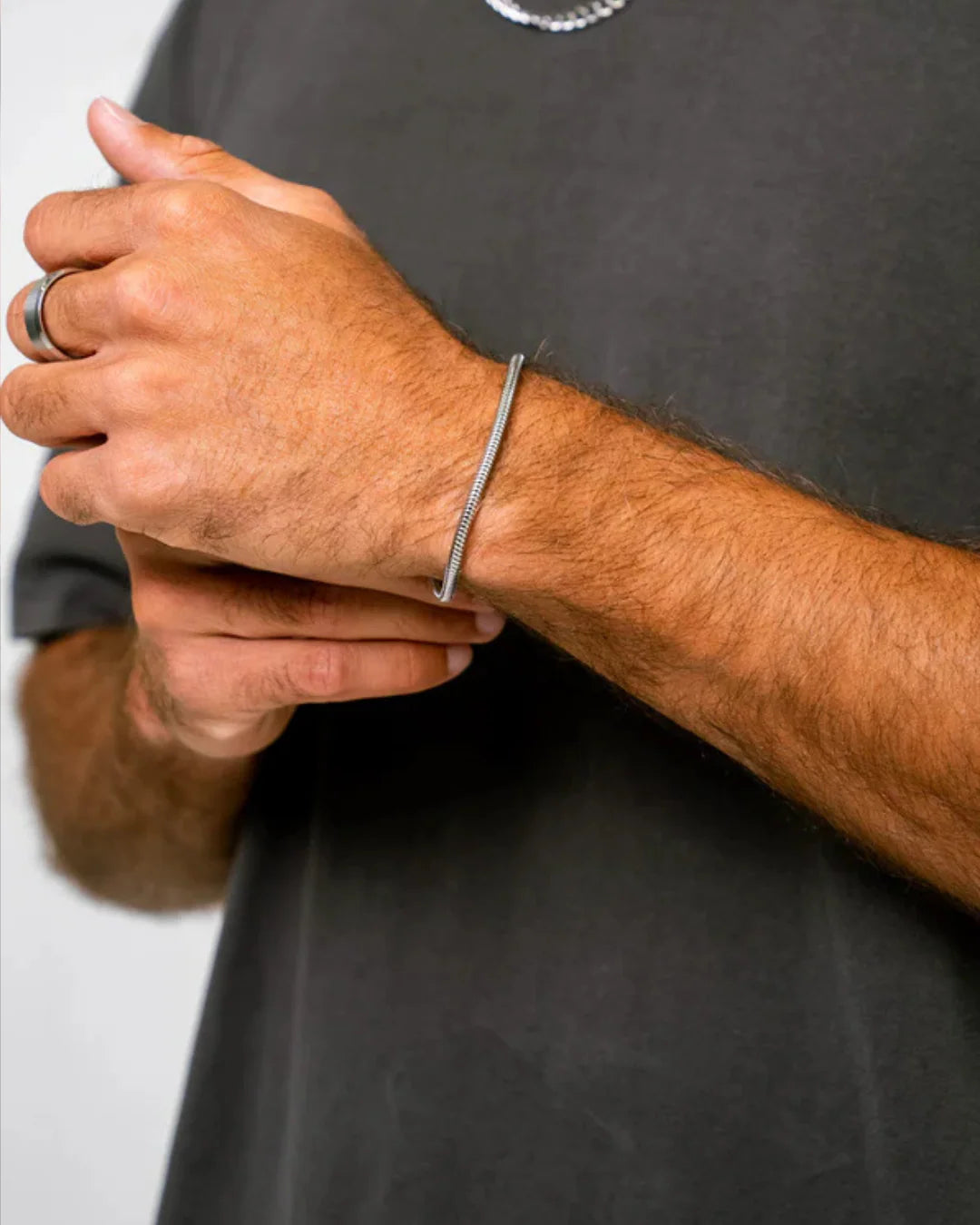 Person wearing a silver bracelet on a plain background