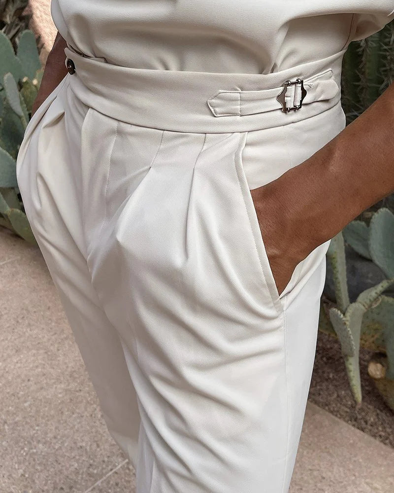 Close-up of a person wearing white pants with a belt, standing in front of cacti.