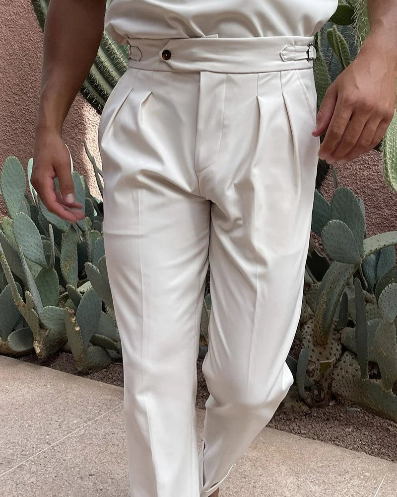 Person wearing a beige outfit with pleated pants against a cactus background