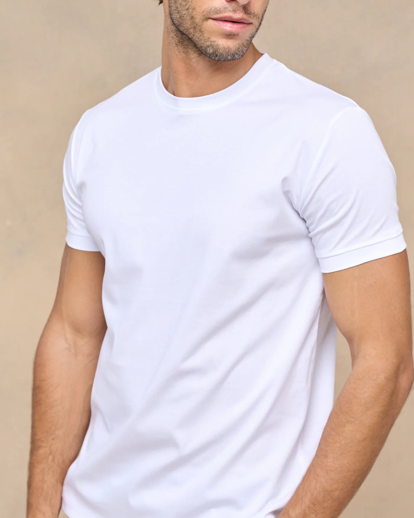 Man wearing a plain white t-shirt against a beige background