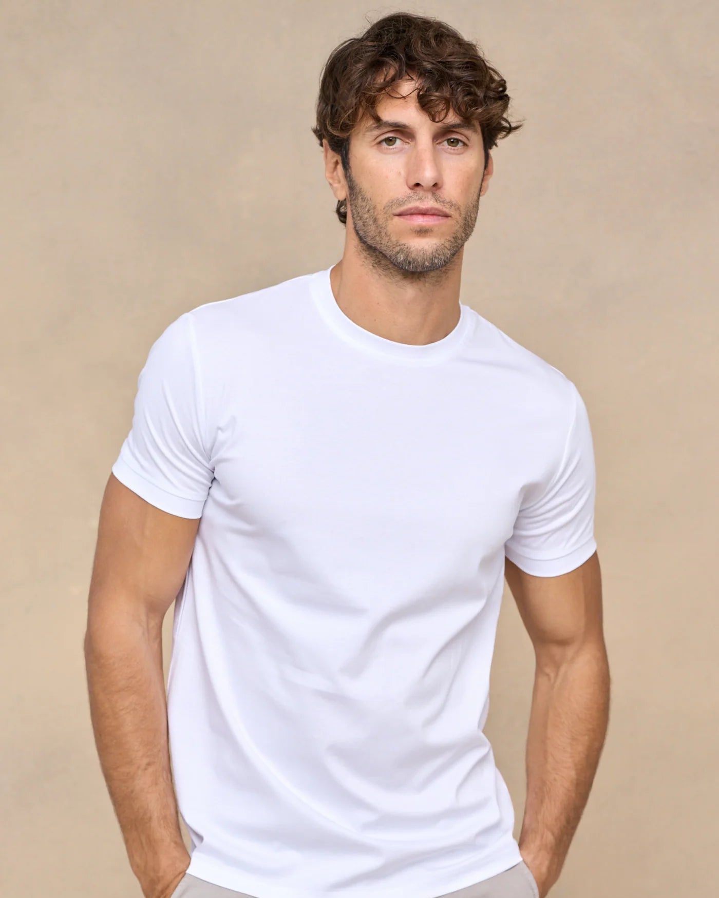 Man wearing a plain white t-shirt against a beige background