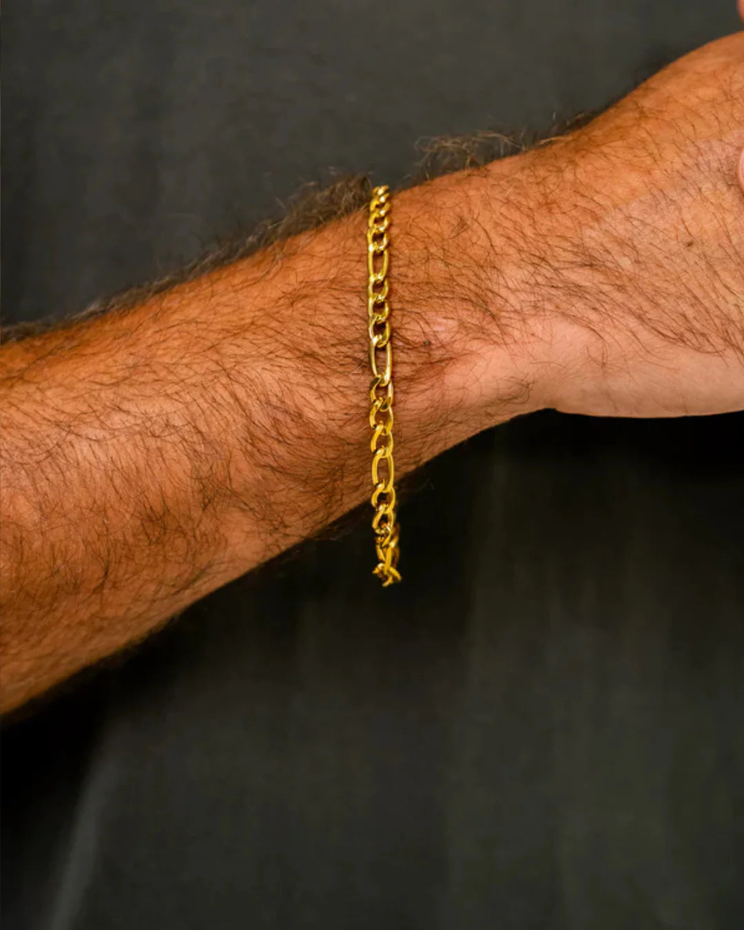 Gold chain bracelet on a person's wrist against a dark background