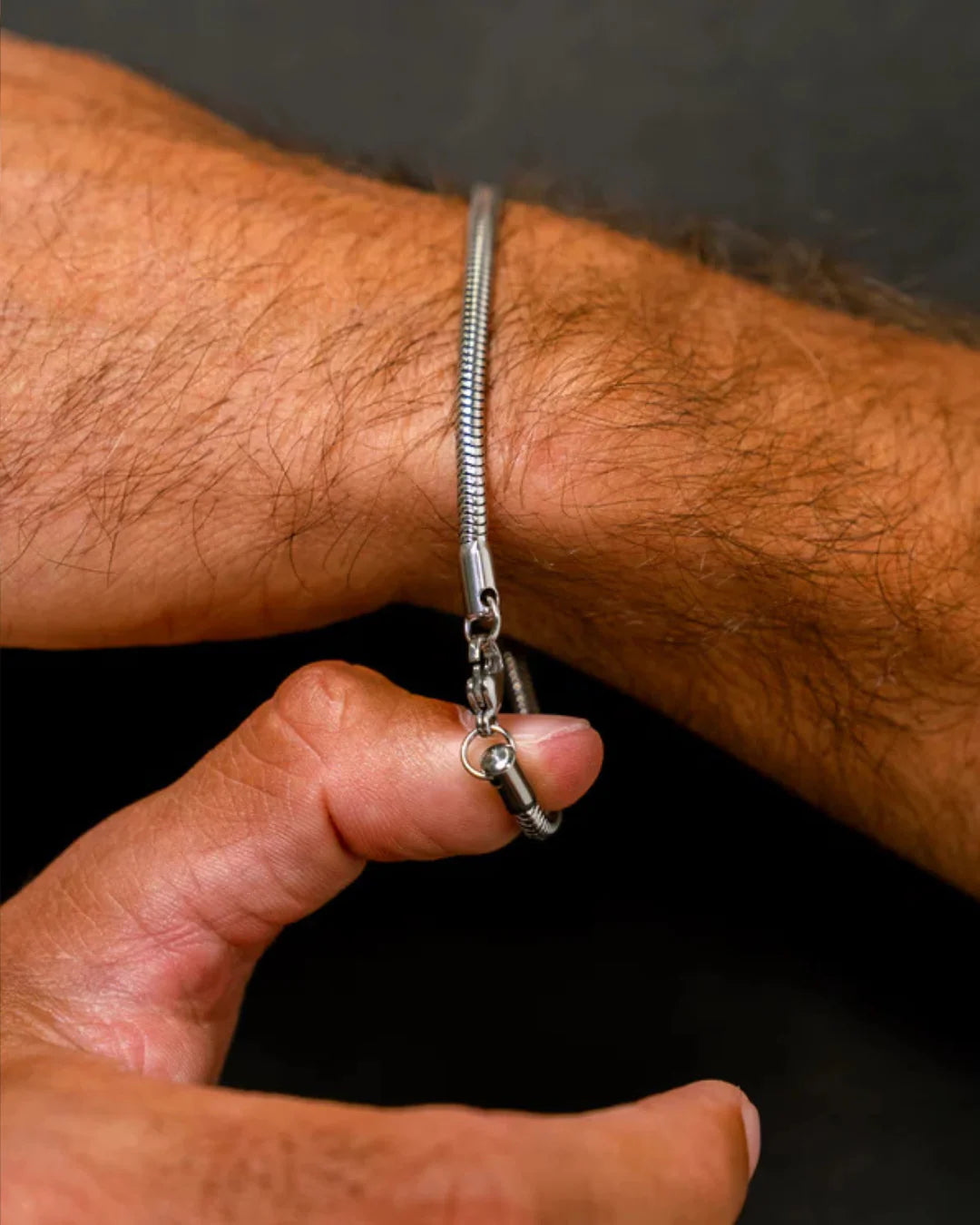 Close-up of a silver bracelet on a wrist with a dark background